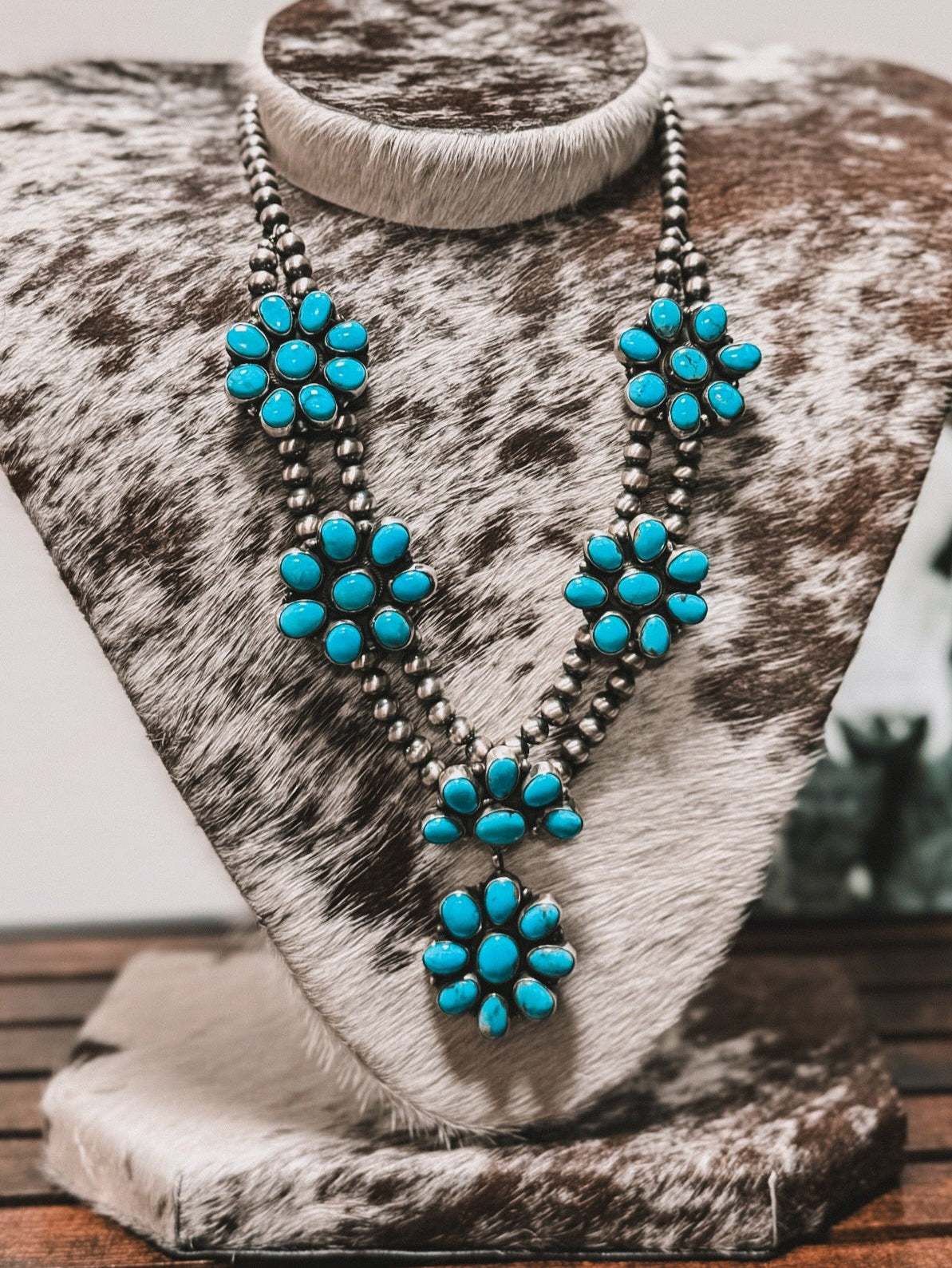 Turquoise necklace on a wooden stand with a cowhide surface